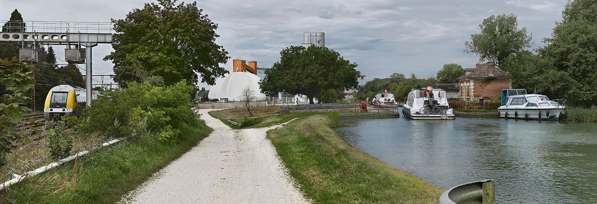 Vue d'ensemble de l'environnement du site de l'écluse 111 du versant Yonne à Brienon-sur-Armançon. De droite à gauche&nbsp;: la maison éclusière, le canal, un silo, la voie ferrée.