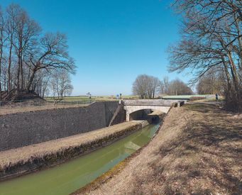 La tranchée du Creusot, bief 13 du versant Yonne, à Saint-Thibault. Au centre, le pont en pierre, avec un des deux escaliers d'accès à la banquette de halage de la tranchée et derrière, le pont plus récent.