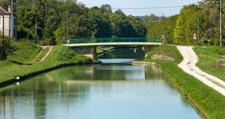 Ancien pont en bois exhaussé en 1893, avec pose d'un tablier métallique à chaussée de tôle emboutie. L'ouvrage, repris à la fin du 20e siècle (bords du tablier et parapets modernes) conserve son tablier métallique. Bief 63 du versant Yonne à Nogent-lès-Montbard.