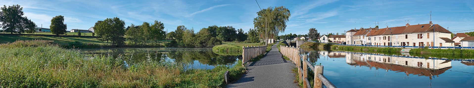 Le bief 03 du versant Méditerranée vu d’aval, de la rive droite. Le réservoir de dépôt à gauche et le déversoir vers le canal sur le chemin de halage. Au fond, la maison éclusière et le site d'écluse 02. Deux petits lavoirs dans la rive gauche. Alignements de maisons le long du chemin de halage, devenu route départementale. Ecuisses.