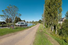 Canal du Nivernais&nbsp;: une bateau de plaisance et un vélo au niveau du site d'écluse 03 du versant Loire. À droite la maison éclusière de ce site et en arrière-plan, le site d'écluse 02.