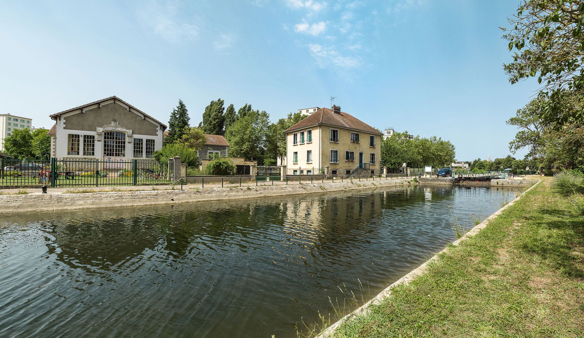 Le site de l’écluse 81 du Batardeau, avec à gauche le moulin dont la façade donnant sur le canal est percée d'une porte monumentale à deux vantaux surmontée d'un blason aux armes de la ville d'Auxerre et flanquée de consoles ornées de triglyphes.