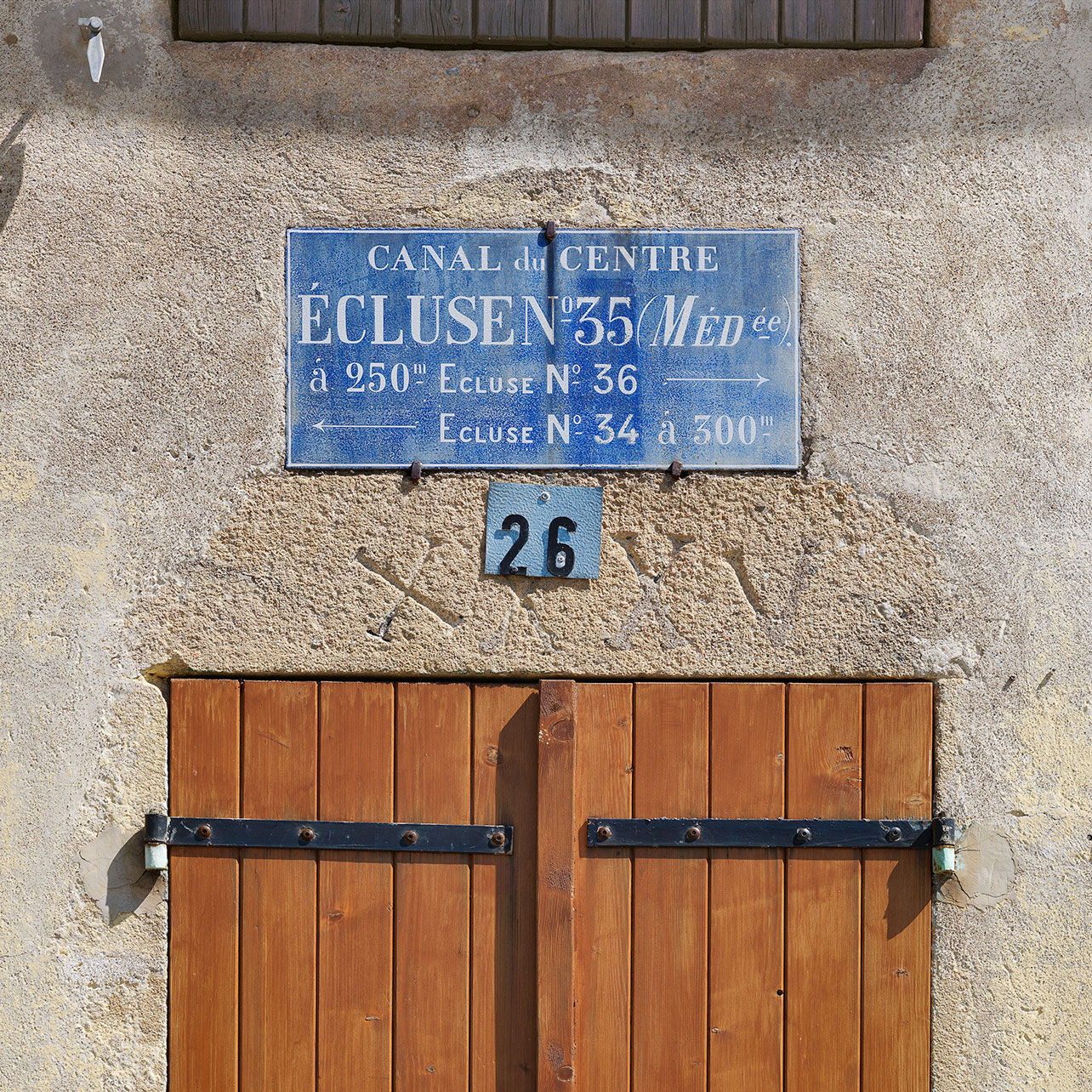 Plaque émaillée et gravure sur le linteau de la maison éclusière du site de l’écluse 26 du versant Méditerranée à Rully, ancien site d’écluse XXXV. La différence de numérotation s’explique par la suppression des sites d’écluse.