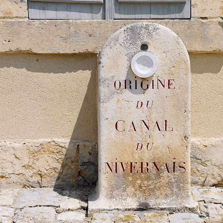 Borne en calcaire portant l’inscription « Origine du canal du Nivernais ». Placée sur le quai devant la maison du receveur de la navigation, aujourd’hui espace d’interprétation du toueur Ampère V, à Saint-Léger-des-Vignes.