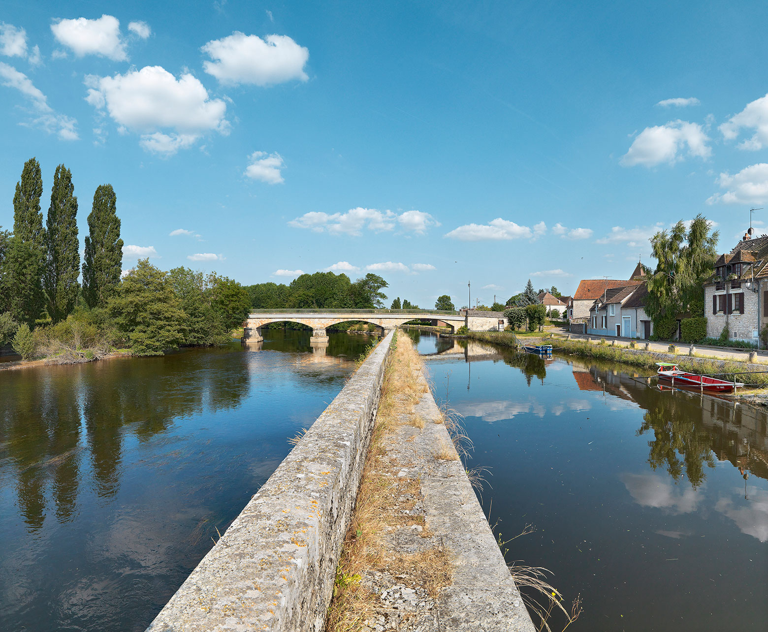 A gauche, la Cure, à droite l’embranchement de Vermenton séparé par une digue. Le pont d’Accolay enjambe les deux voies d’eau en arrière-plan.